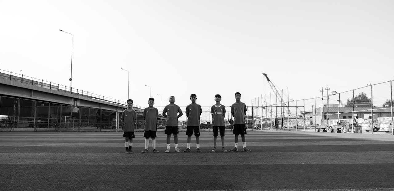 Black and white photo of a youth soccer team lined up on a field beneath an overpass.